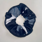 Navy blue, gray, and white scrunchie on a light gray background